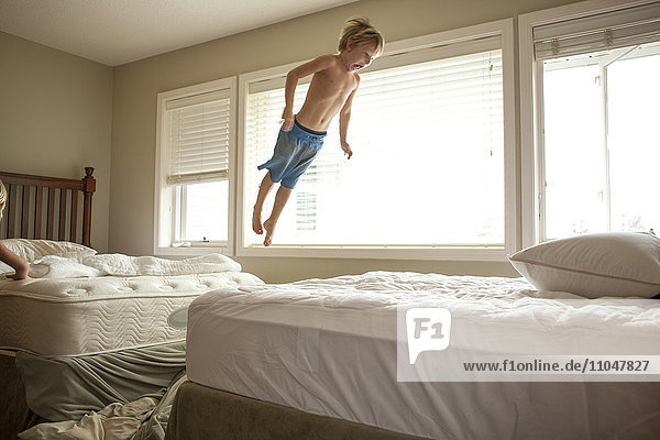 Caucasian boy jumping on bed