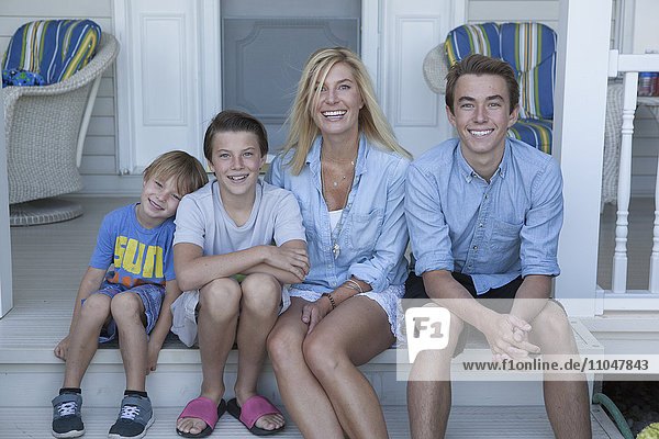 Caucasian mother and sons smiling on porch