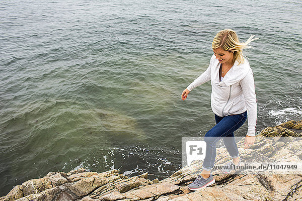 Kaukasische Frau  die auf Felsen am Meer läuft