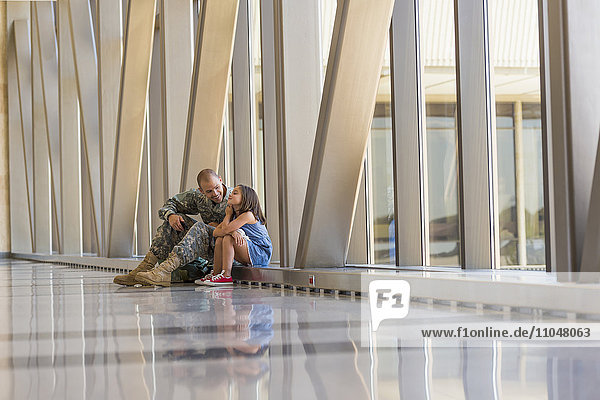 Heimkehrender Soldat im Gespräch mit seiner Tochter am Flughafen