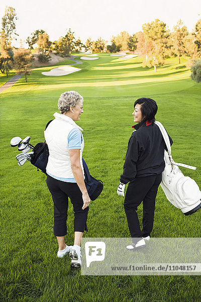 Frauen tragen Golfschläger auf dem Golfplatz