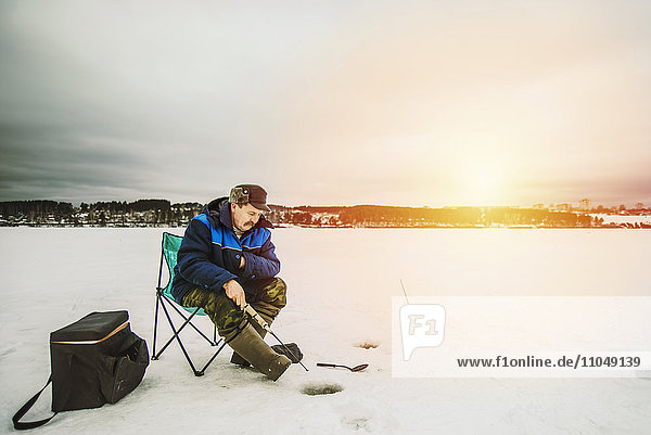 Mann beim Eisfischen im zugefrorenen See
