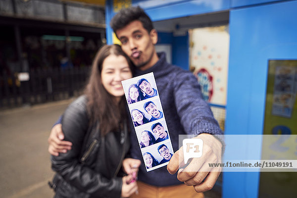 Ehepaar zeigt Fotostreifen aus dem Fotoautomaten