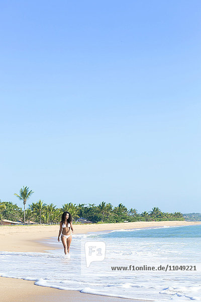 Gemischtrassige Frau geht am Strand spazieren