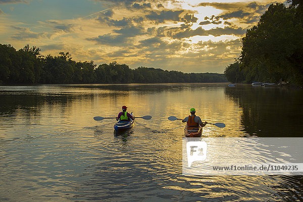 Couple kayaking in river at sunset