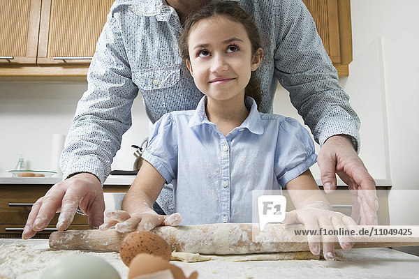 Mother teaching daughter to bake in kitchen