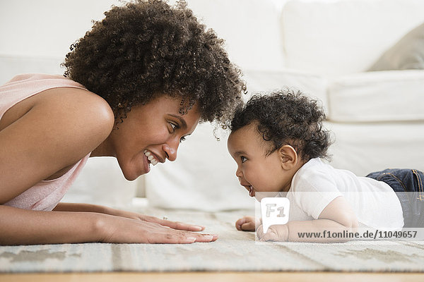 Mother playing face to face with baby son on floor