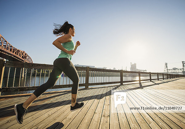 Caucasian woman jogging on urban waterfront