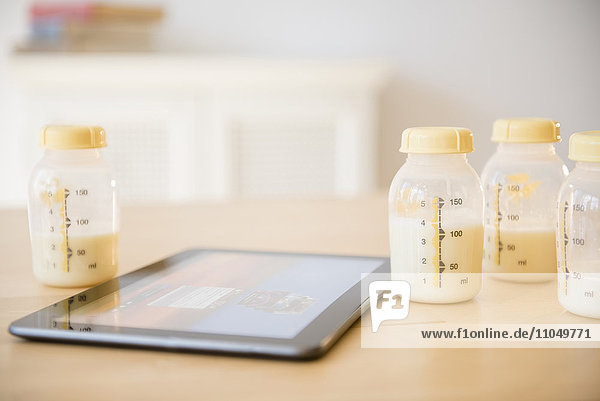 Digitales Tablet in der Nähe von Muttermilchflaschen