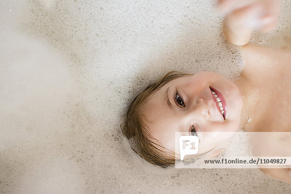 Caucasian girl smiling in bubble bath