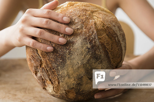 Hispanische Frau hält runden Laib Brot