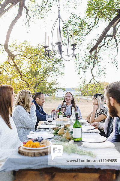 Freunde trinken Wein an einem Tisch im Freien
