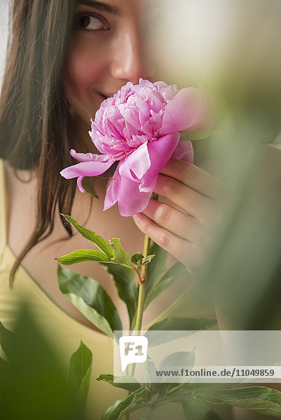 Hispanische Frau riecht an rosa Blume