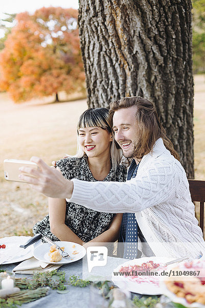 Paar nimmt Selfie am Tisch im Freien