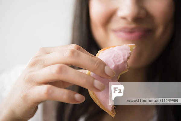 Hispanic woman eating donut with pink icing