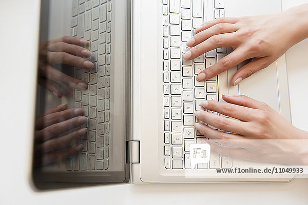 Hände einer hispanischen Frau  die auf einem Laptop tippt