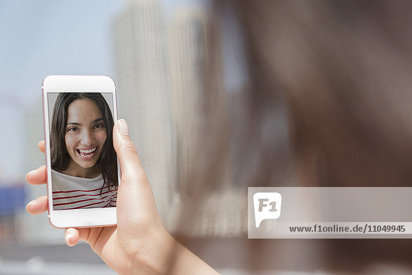 Lächelnde hispanische Frau  die für ein Selfie mit ihrem Handy posiert
