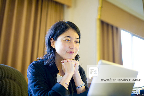 Smiling Japanese businesswoman reading laptop