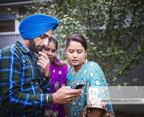 Family in traditional Indian clothing using cell phone