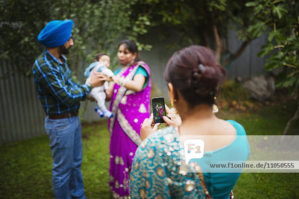 Frau fotografiert Familie mit Mobiltelefon