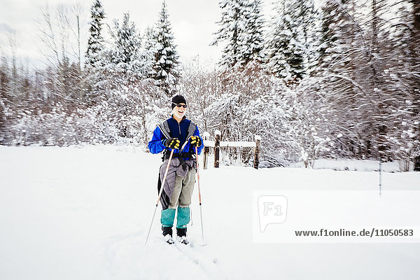 Caucasian woman cross-country skiing in snowy field