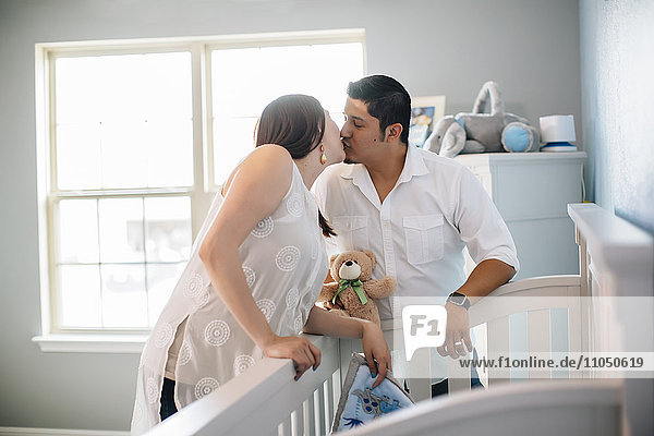 Hispanic couple kissing in nursery