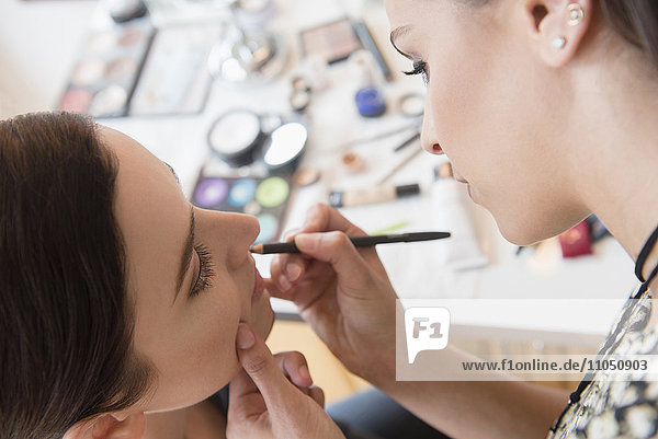 Woman having makeup applied by stylist