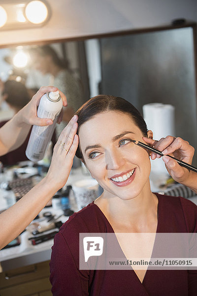 Woman having makeup applied by stylists