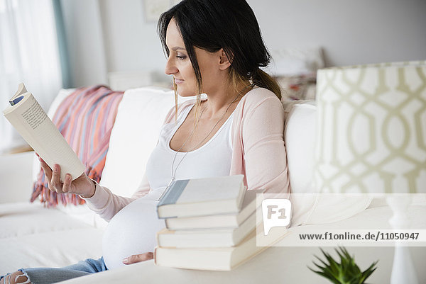 Pregnant Caucasian woman reading baby books