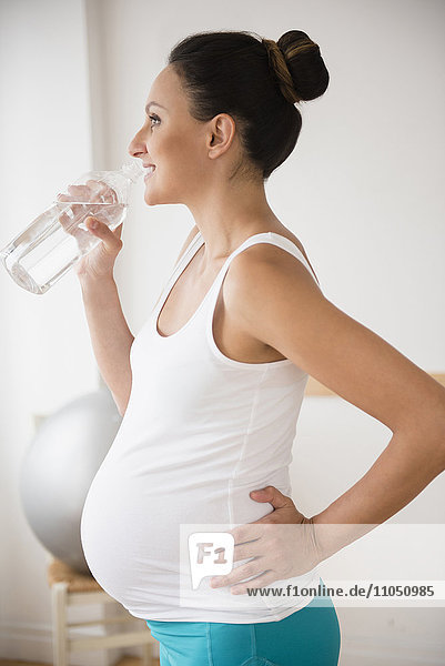 Pregnant Caucasian woman drinking water bottle