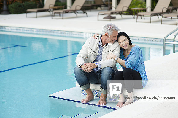 Kaukasisches Paar  das sich am Pool umarmt