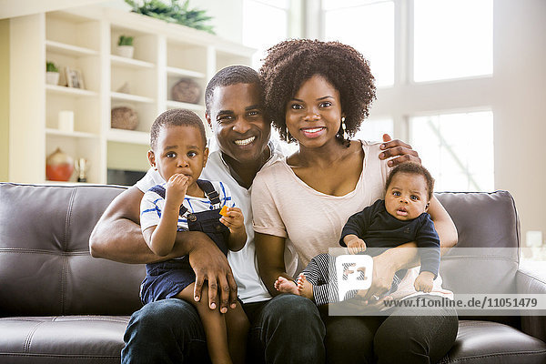 Smiling Black family posing on sofa