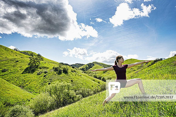Caucasian woman doing yoga on hill