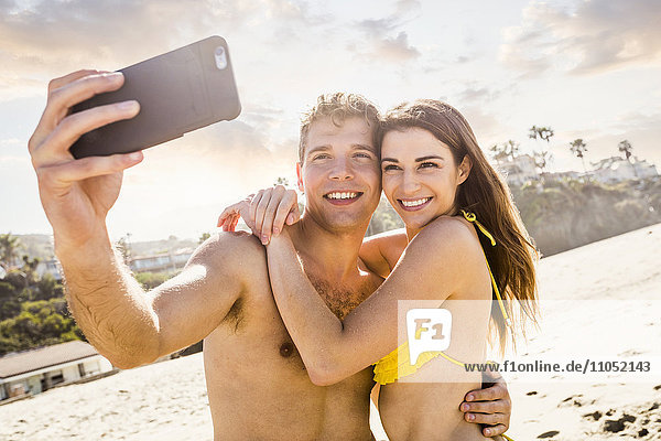 Caucasian couple taking selfie on beach