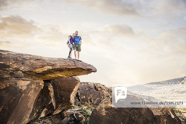 Caucasian couple on rock formation admiring landscape