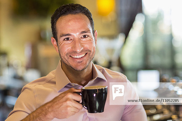 Hispanischer Barista trinkt Kaffee im Coffeeshop