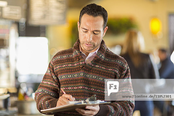 Hispanischer Geschäftsmann schreibt in einem Café