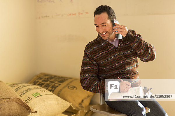 Hispanischer Unternehmer  der in einem Geschäft telefoniert