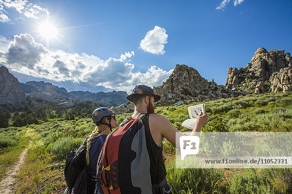 Kaukasisches Paar liest Reiseführer in der Nähe eines Berges