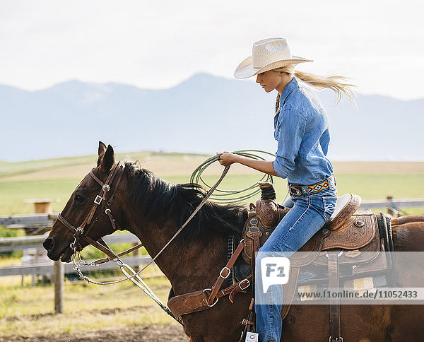 Kaukasisches Cowgirl mit Lasso auf dem Pferderücken