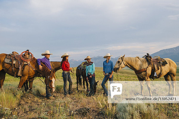Cowboy and cowgirls with horses on ranch