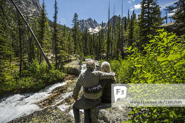 Kaukasisches Paar  das sich auf einem Felsen am Bergfluss umarmt