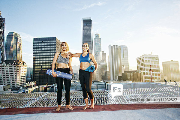 Frauen halten Yogamatten auf einem städtischen Hausdach
