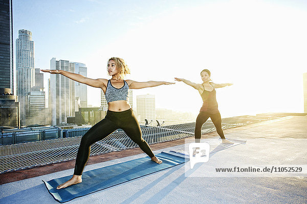 Frauen üben Yoga auf einem städtischen Hausdach