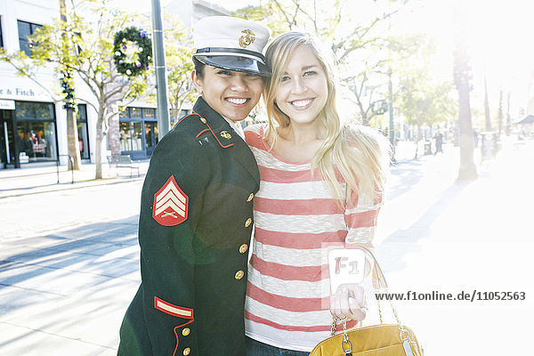 Asian soldier and friend smiling outdoors