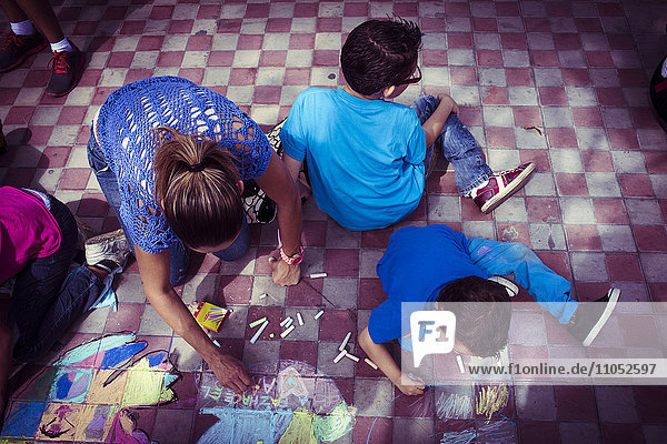 Hispanic family drawing with chalk on floor