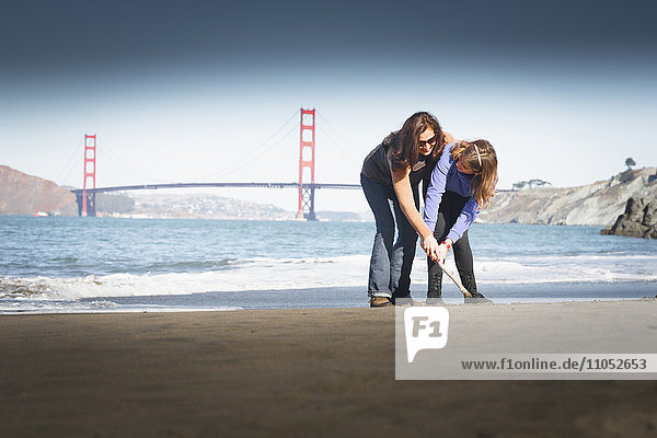 Mutter und Tochter zeichnen im Sand am Strand  San Francisco  Kalifornien  Vereinigte Staaten