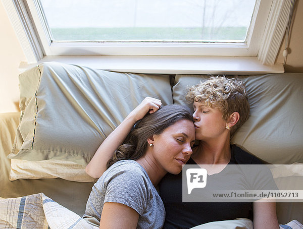 Caucasian lesbian couple kissing in bed