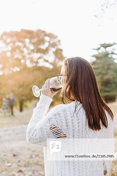 Caucasian woman drinking wine in rural field