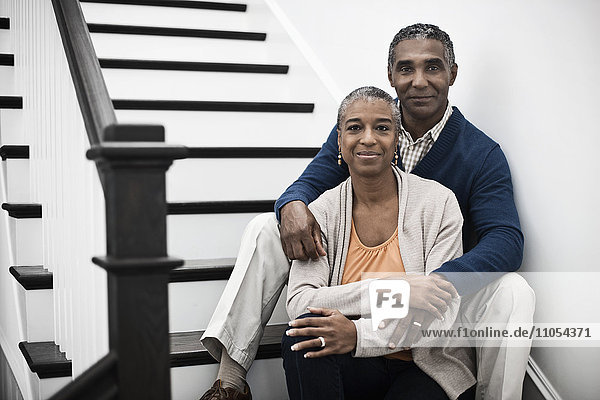 A mature couple  man and woman  sitting on the stairs together at home.